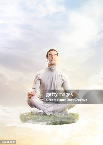 man in yoga position, floating on a patch of grass - levitation stock-fotos und bilder