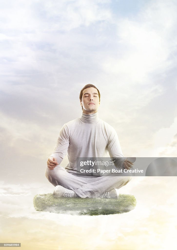 Man in yoga position, floating on a patch of grass