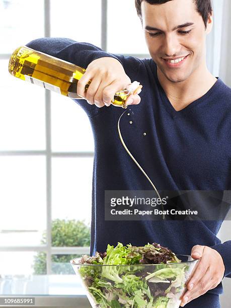 man pouring olive oil on to fresh green salad - salladsskål bildbanksfoton och bilder