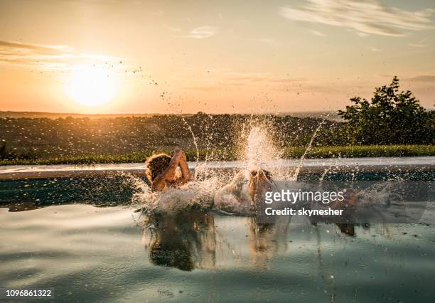 jumping into the pool at sunset! - jumping in pool stock pictures, royalty-free photos & images