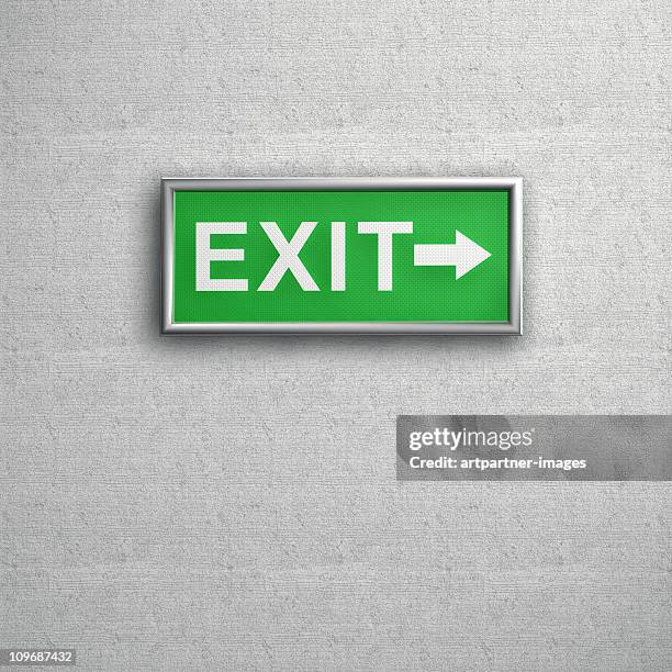 green exit sign on a grey wall - exit sign stock pictures, royalty-free photos & images