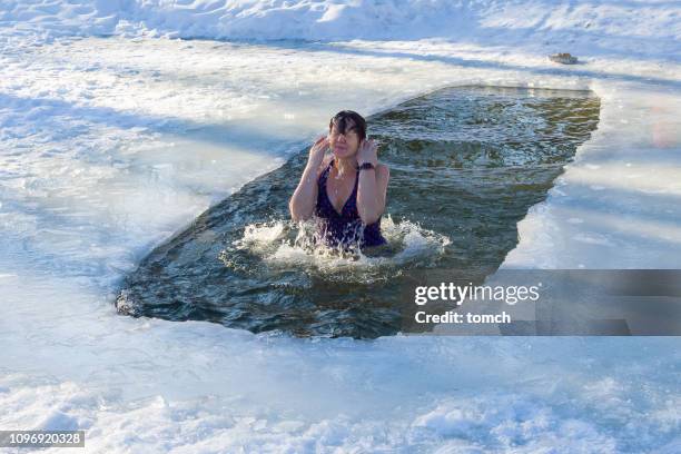 eine frau ergibt sich aus dem eisloch. tauftag - woman ice stock-fotos und bilder