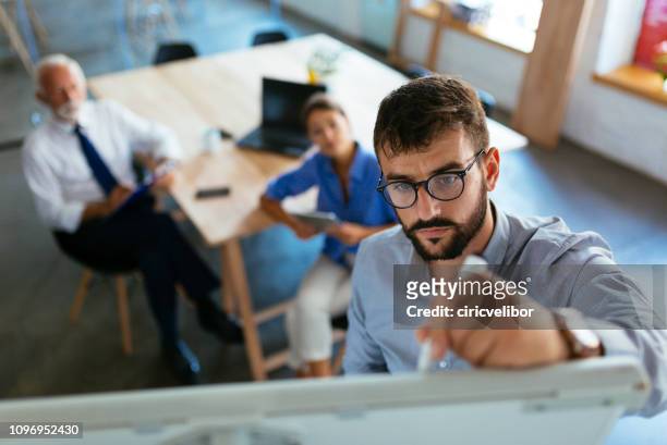 mid adult businessman writing a business plan on whiteboard during a meeting at conference room - business plan stock pictures, royalty-free photos & images