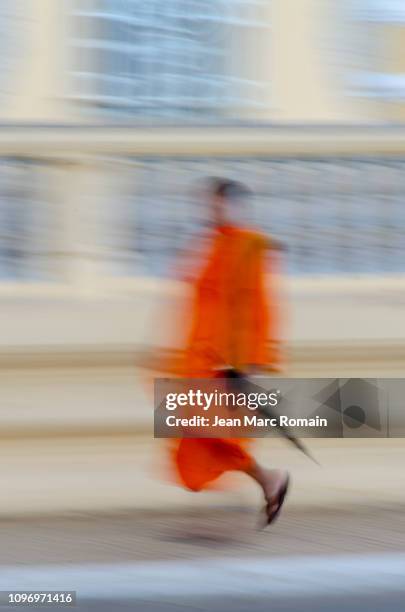 a buddhist monk walking down the street - palais royal stockfoto's en -beelden
