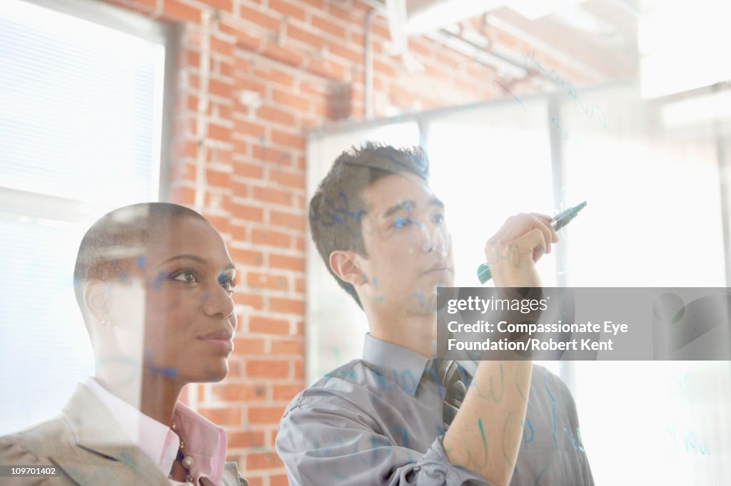 Business people writing on clear surface