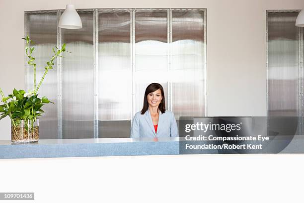 smiling professional woman sitting at a desk - secretary stock pictures, royalty-free photos & images