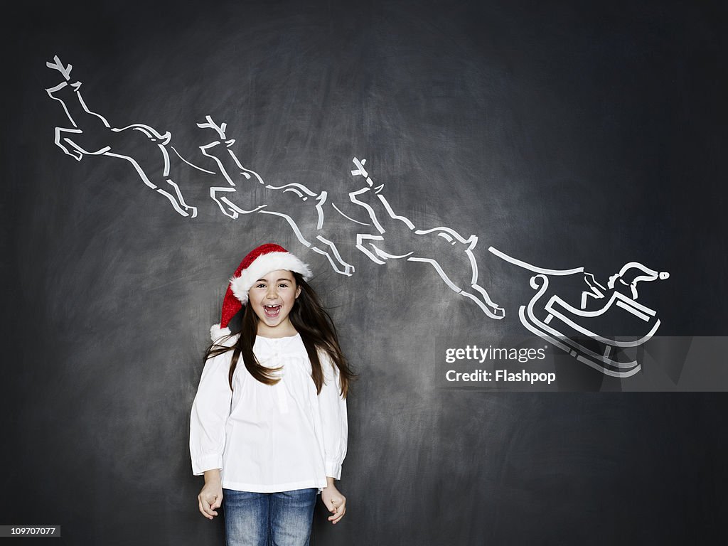 Girl wearing santa hat with santa on a sleigh