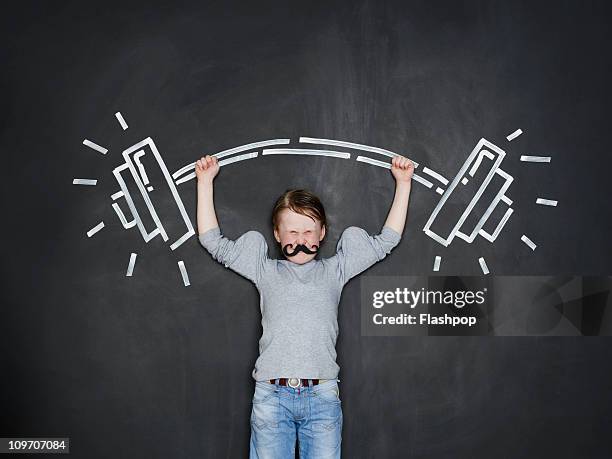 boy as a strongman lifting heavy weight - wit blackboard - fotografias e filmes do acervo