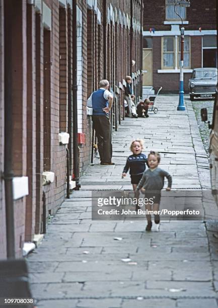 Two boys running down a terraced street in Manchester, England in 1976.
