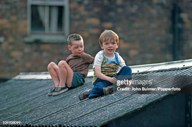 Two boys sitting on a shed roof in Manchester, England in 1976.