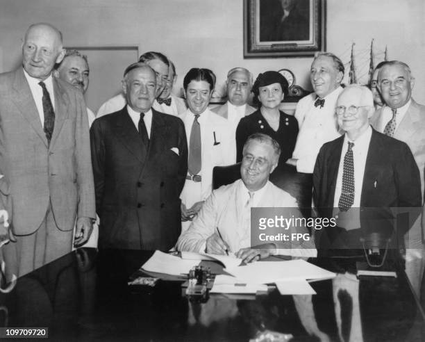 President Franklin D. Roosevelt signs the Social Security Act, 14th August 1935. From left to right, Robert Lee Doughton, chairman of the House Ways...