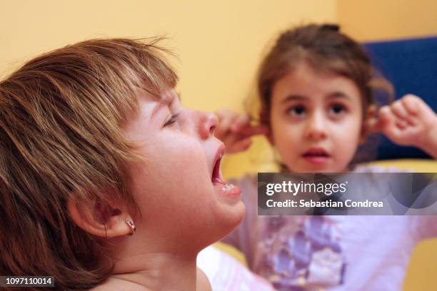 in the evening at bedtime, the little sister is crying and the big one slamming her ears, siblings, romania - crying sibling stock pictures, royalty-free photos & images