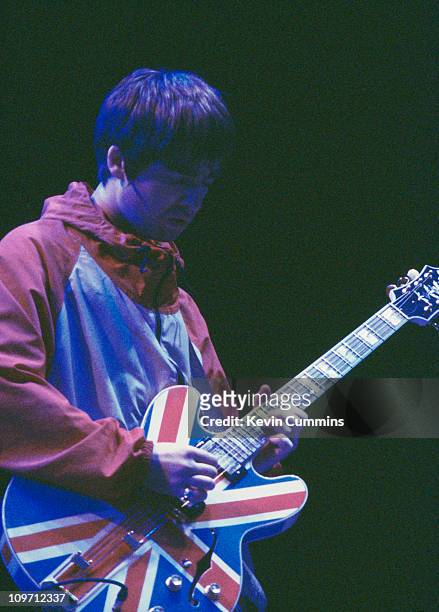 Guitarist Noel Gallagher playing a Union Jack guitar during a performance by British pop group Oasis, circa 1995.