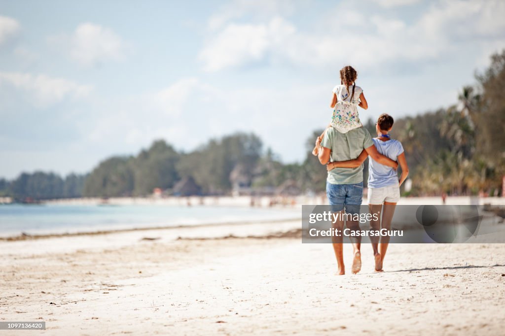 Familie mit einer Tochter, die zu Fuß am Sandstrand