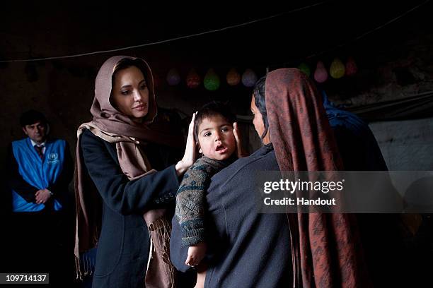 In this handout provided by the UNHCR, UNHCR Goodwill Ambassador, Angelina Jolie, meets with Khanum Gul a mother of 8 and her youngest son, Samir at...