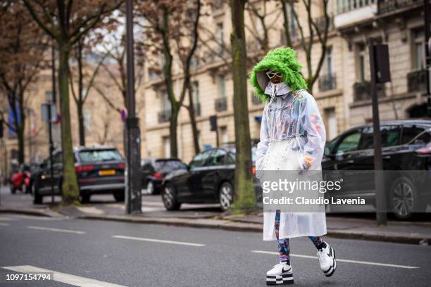 Michelle Elie, wearing a long see through jacket with green fur details and black and white Nike sneakers, is seen in the streets of Paris before the...
