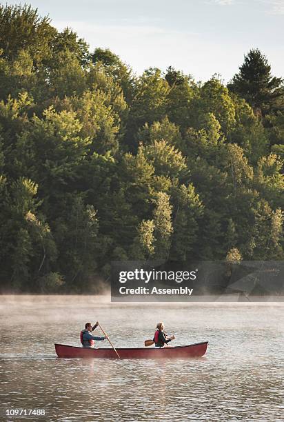 couple paddles a canoe at sunrise on a lake - vermont fotografías e imágenes de stock