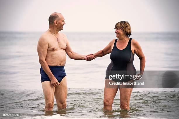 happy senior couple in sea - women's swimwear stock pictures, royalty-free photos & images