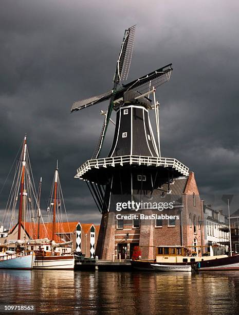 cities; dutch windmill near harbor with stormy sky - haarlem stock pictures, royalty-free photos & images