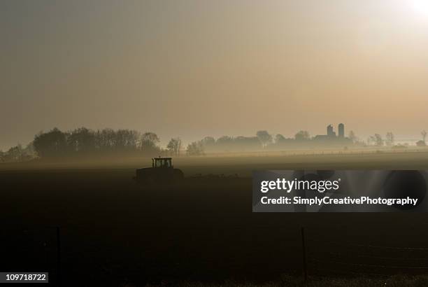 sagoma del trattore su un campo di nebbia alba - campo arato foto e immagini stock