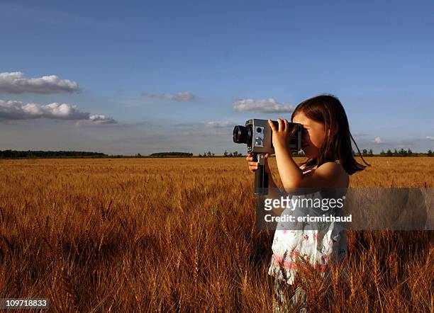 bambina in piedi in campo e riprese con macchina fotografica d'epoca - film director foto e immagini stock