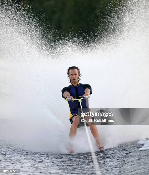 man towed barefoot behind boat - waterskiing stock pictures, royalty-free photos & images