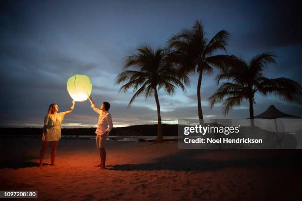 couple with lantern on beach by sunset - curaçao stock pictures, royalty-free photos & images