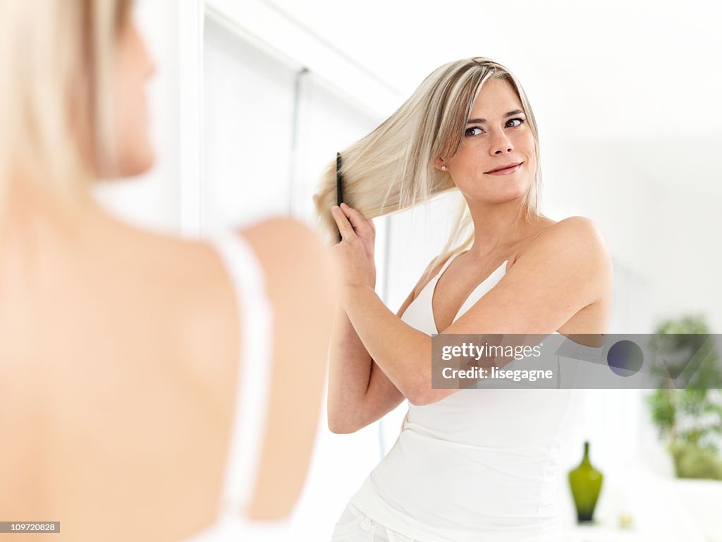 Woman combing hair in mirror