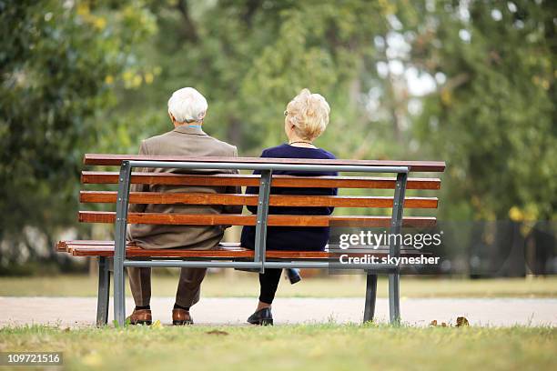 rear view of a senior couple sitting outdoor on bench. - bench stock pictures, royalty-free photos & images