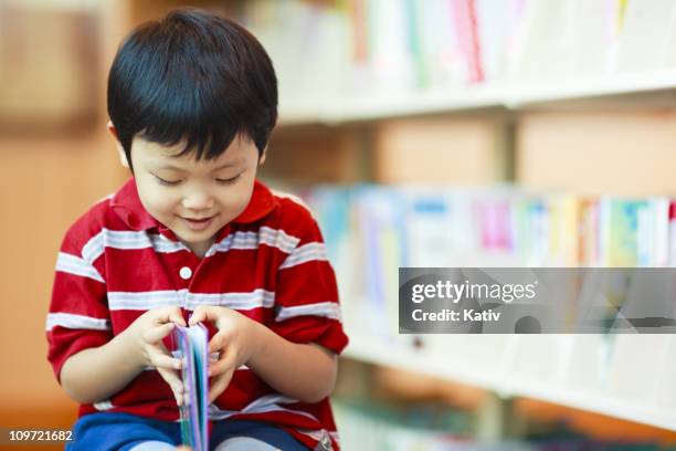cute boy at the library - pages turning stock pictures, royalty-free photos & images