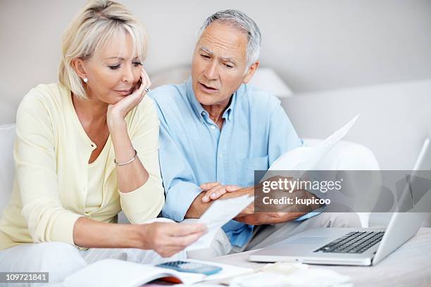 tensed mature couple discussing their monthly expenses at home - calculator stock pictures, royalty-free photos & images