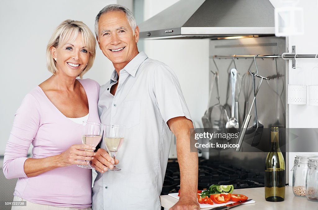 Happy couple together holding champagne glasses at kitchen