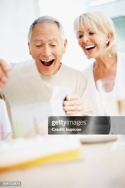 surpris femme homme senior avec le cadeau d'anniversaire d'ouverture - cadeau danniversaire photos et images de collection