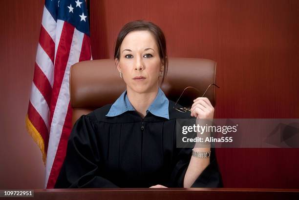 young female judge at the bench with serious look - serious crimes court stock pictures, royalty-free photos & images