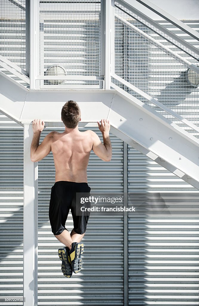 Atleta facendo un pull-up in una scena urbana con copia