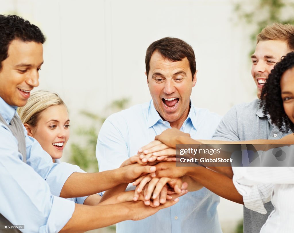Excited business people with their hands together in unity