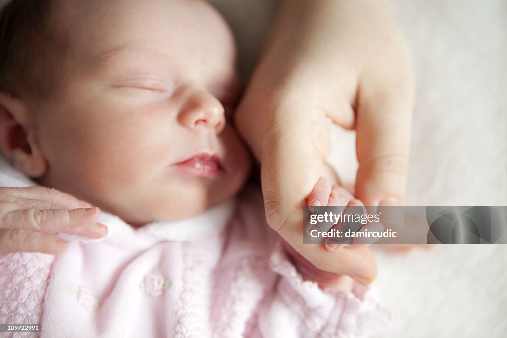 Newborn baby holding mother's hand