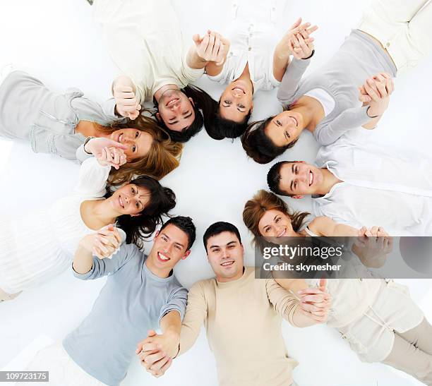 young people lying in a circle with united hands. - children circle floor stock pictures, royalty-free photos & images