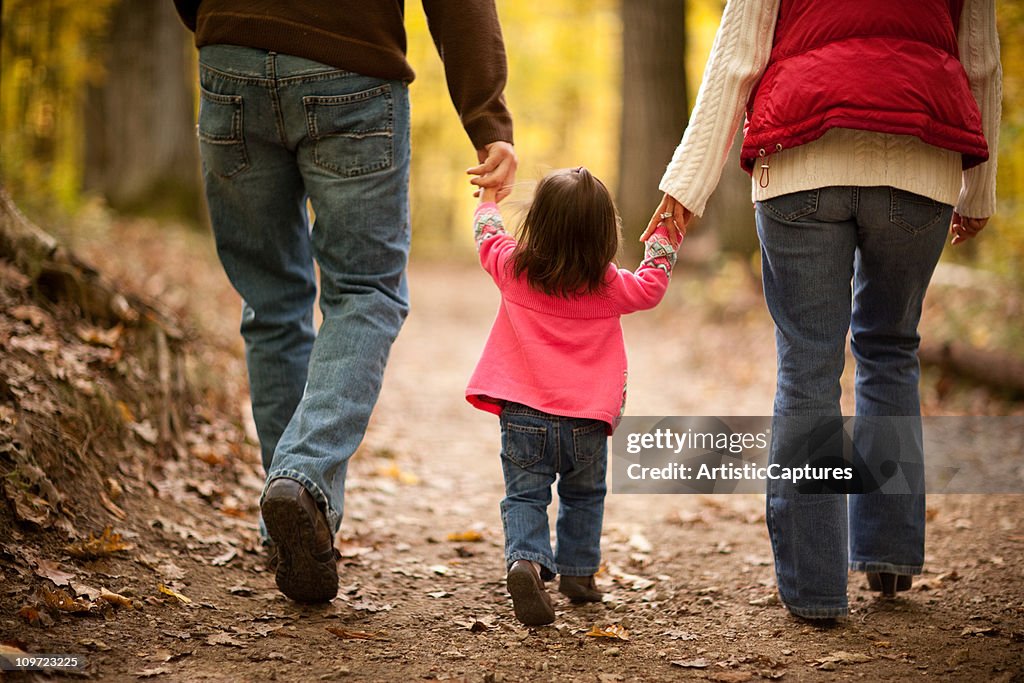 Família de três andar no trilho através de outono floresta,