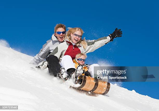 family laughing and sledding downhill - summit co stock pictures, royalty-free photos & images