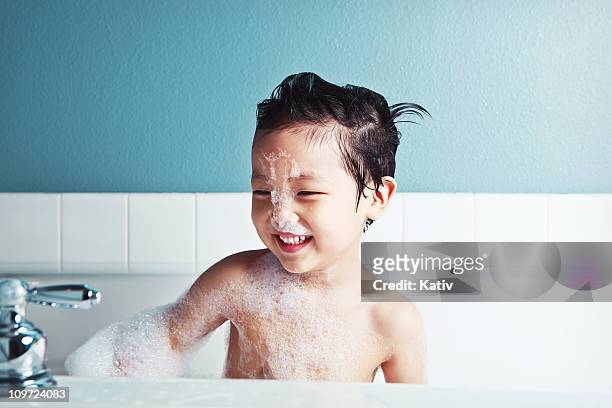 asian boy taking a bath and smiling - bubbelbad stockfoto's en -beelden