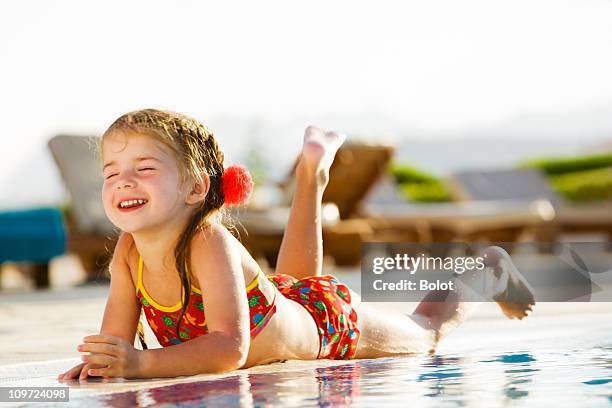 little girl lying by edge of pool on sunny day - kids pool games stock pictures, royalty-free photos & images