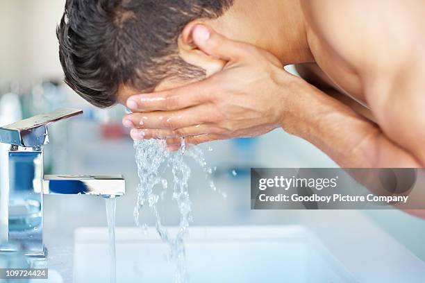 young guy cleansing face with water at the sink - washing face stock pictures, royalty-free photos & images