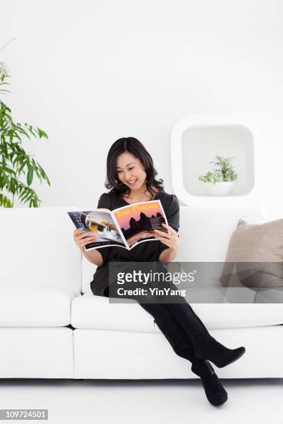 japanese woman sitting on white sofa, reading magazine at home - women in nylons 個照片及圖片檔