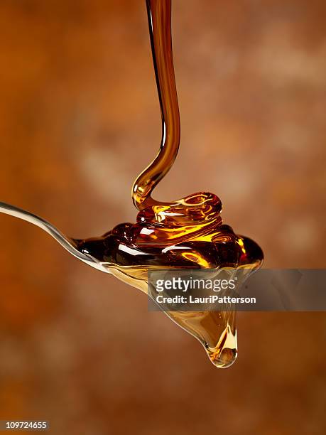 pouring maple syrup over a spoon - honing stockfoto's en -beelden