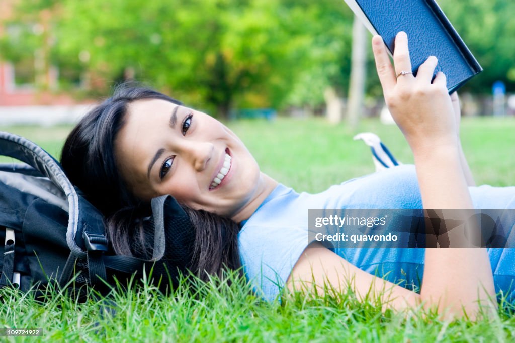 Asian Teenage Female Student Reading on Campus Lawn