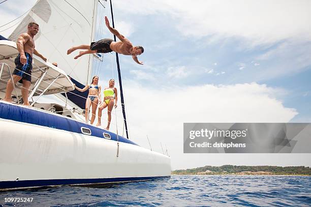 man jumping off sailboat into caribbean sea - roatan stock pictures, royalty-free photos & images