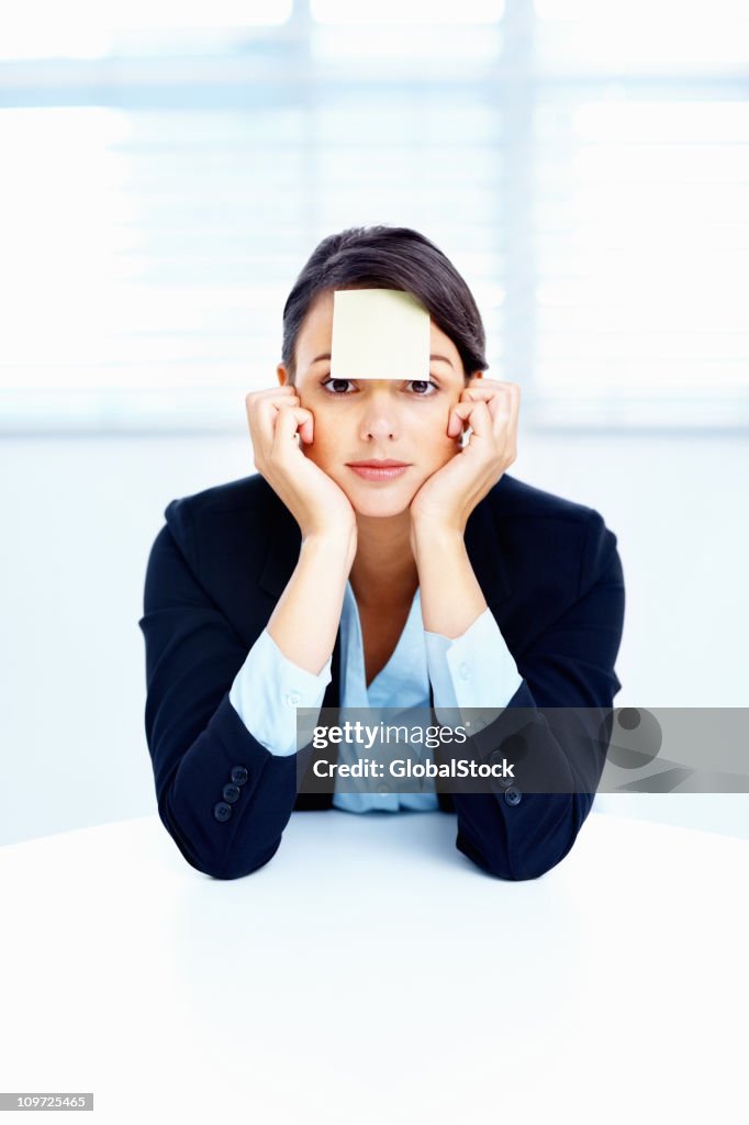 Business woman with an adhesive note on forehead