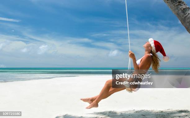 tropical christmas woman on a swing - santa hat stock pictures, royalty-free photos & images