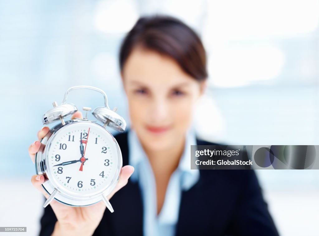 Mid adult businesswoman holding an alarm clock